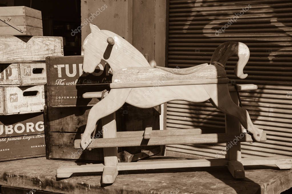 TEL AVIV-YAFO, ISRAEL - FEBRUARY 18, 2014: Wooden rocking horse and old Tuborg beer and 7up boxes for sale. Jaffa flea market is one of the popular attractions for tourists and locals in Tel Aviv-Yafo. Sepia photo.