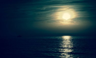 Aya doğru yelken balıkçı veya eğlence gemi silueti. Karanlık gökyüzü ve bulutlar. Moonwalk. Su yansıması. Gece güzel deniz manzarası. Doğa fikir ile uyum. Gizem arka plan.