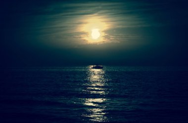 Aya doğru yelken balıkçı veya eğlence gemi silueti. Karanlık gökyüzü ve bulutlar. Moonwalk. Su yansıması. Gece güzel deniz manzarası. Doğa fikir ile uyum. Gizem arka plan.