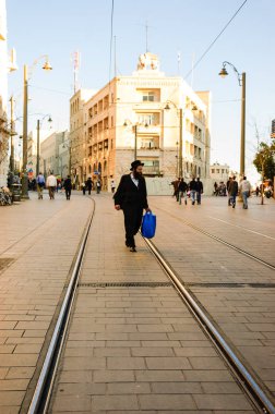 Kudüs, Israil-19 Şubat 2014: tanımlanamayan Ortodoks Yahudi Jaffa Road caddesinde hafif raylı tramvay treninin treni üzerinde yürüyor. 2011 yılından bu yana işletilen ve her gün 130.000 kişi kadar hizmet vermektedir.