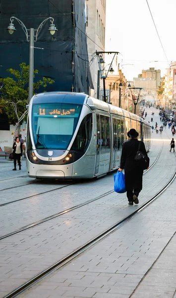 JERUSALEM, ISRAEL - 19 DE FEBRERO DE 2014: Tren ligero de tranvía y Judio ortodoxo caminando en el ferrocarril en la calle Jaffa Road. Tranvía opera desde 2011 y atiende hasta 130.000 personas cada día . — Foto de Stock