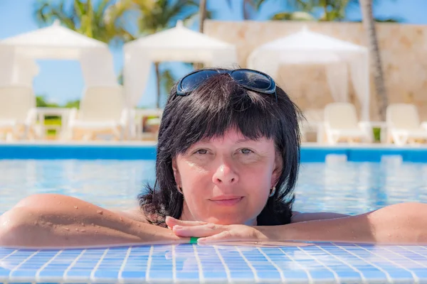 Mujer está acostada cerca de la piscina — Foto de Stock