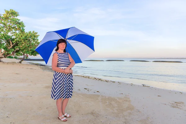 Брюнетка жінка з пляжною парасолькою — стокове фото
