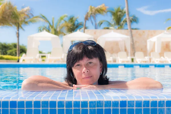 Mulher está deitada perto da piscina — Fotografia de Stock