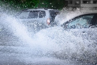 Araba yağmuru su sıçratıyor.