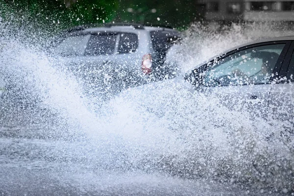 Araba yağmuru su sıçratıyor.