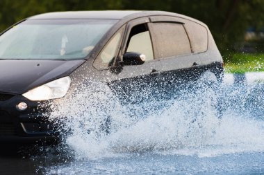 Araba yağmuru su sıçratıyor.