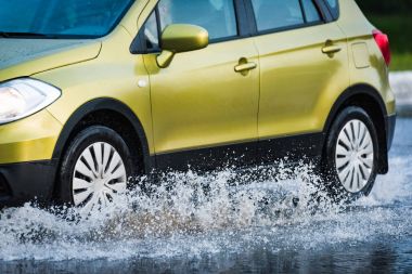 Araba yağmuru su sıçratıyor.