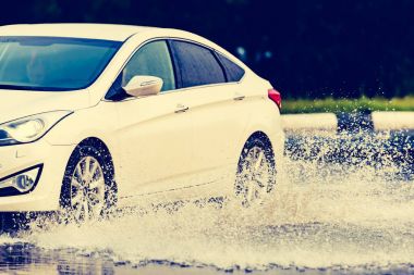 Araba yağmuru su sıçratıyor.