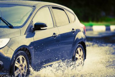 Araba yağmuru su sıçratıyor.