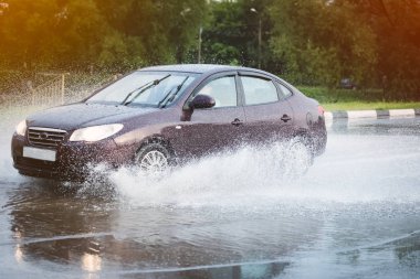 Araba yağmuru su sıçratıyor.