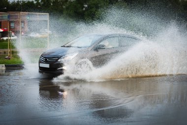 Araba yağmuru su sıçratıyor.