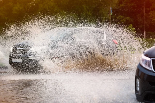 Araba yağmuru su sıçratıyor.