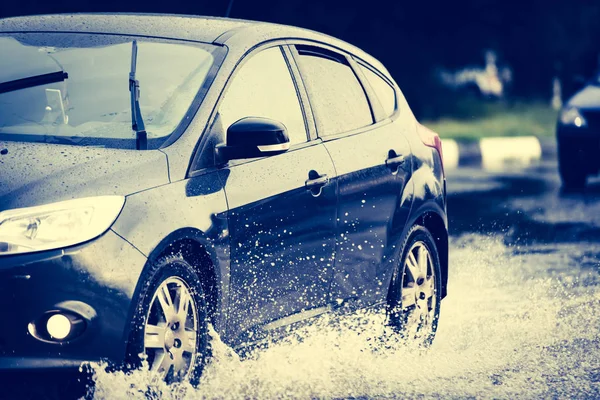 Araba yağmuru su sıçratıyor.