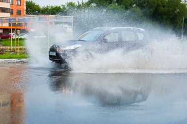 Araba yağmuru su sıçratıyor.