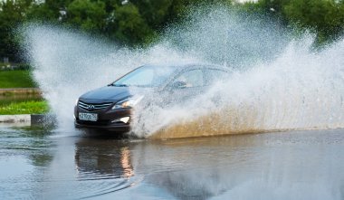 Araba yağmuru su sıçratıyor.