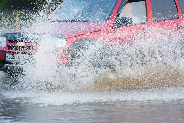 Автомобильная дождевая лужа с брызгами воды — стоковое фото