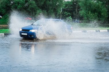 Araba yağmuru su sıçratıyor.