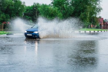 Araba yağmuru su sıçratıyor.