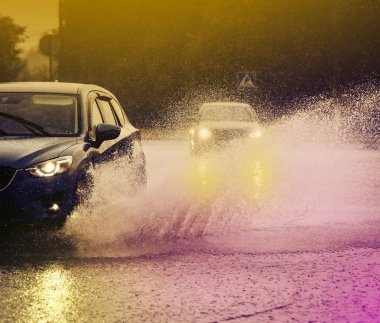 Araba yağmuru su sıçratıyor.