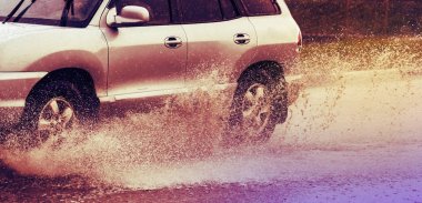 Araba yağmuru su sıçratıyor.