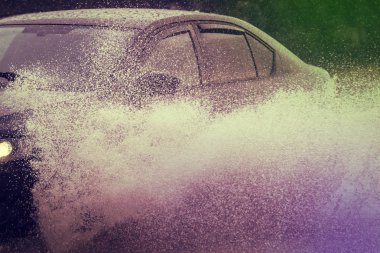 Araba yağmuru su sıçratıyor.