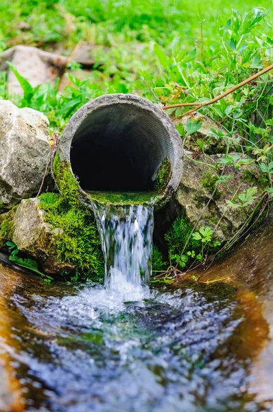 Pipe from the ground flowing ecological clean water — Stock Photo, Image