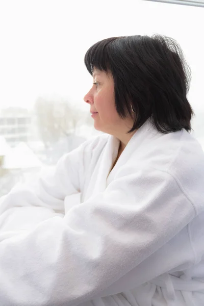 Middelbare leeftijd vrouw door het raam — Stockfoto