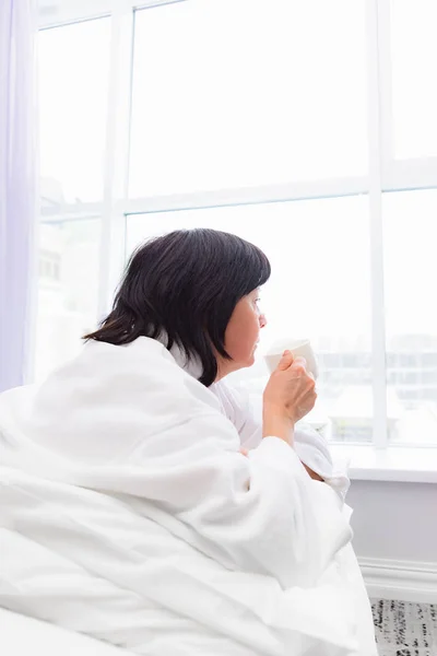 Kvinna på morgonen i sängen med en kopp kaffe — Stockfoto