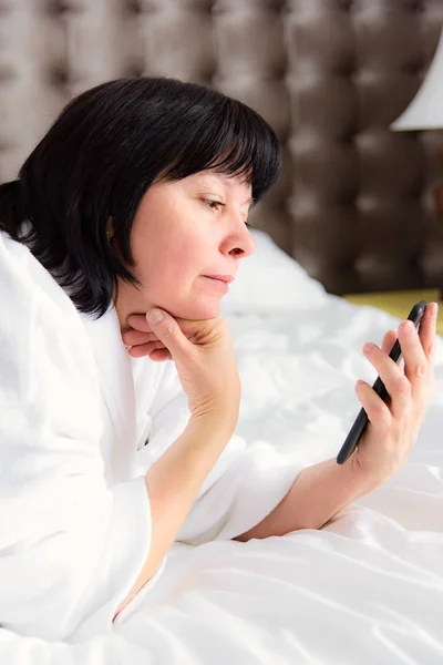 Mulher com telefone na cama — Fotografia de Stock