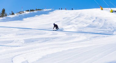 Bulgaristan. Bansko. 10 Şubat 2020. Büyük kar tarlasında kayak yapan kayakçı. Kar tozu sıçratıyor.
