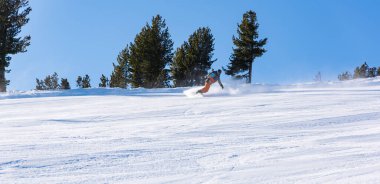 Bulgaristan. Bansko. 10 Şubat 2020. Büyük kar tarlasında kayak yapan kayakçı. Kar tozu sıçratıyor.