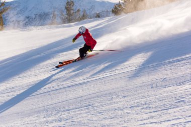 Bulgaristan. Bansko. 10 Şubat 2020. Büyük kar tarlasında kayak yapan kayakçı. Kar tozu sıçratıyor.