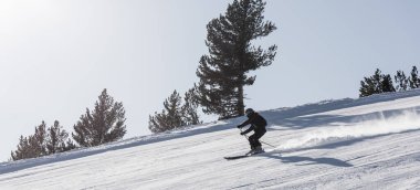 Bulgaristan. Bansko. 10 Şubat 2020. Büyük kar tarlasında kayak yapan kayakçı. Kar tozu sıçratıyor.