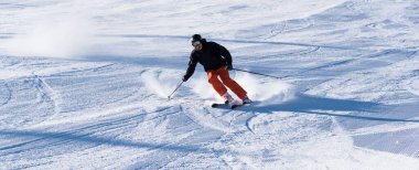 Bulgaristan. Bansko. 10 Şubat 2020. Büyük kar tarlasında kayak yapan kayakçı. Kar tozu sıçratıyor.