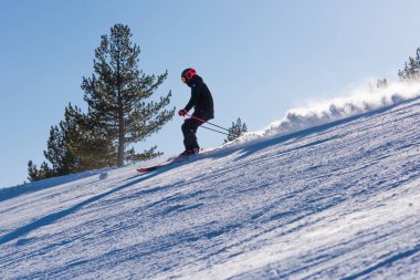 Bulgaristan. Bansko. 10 Şubat 2020. Büyük kar tarlasında kayak yapan kayakçı. Kar tozu sıçratıyor.