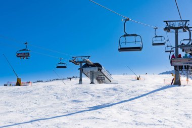 Bulgaristan. Bansko. 10 Şubat 2020 'de Bansko' da bir tatil köyünde. Karlı kayak pistleri ve sandalye kaldırma istasyonları. Güneşli bir günde mavi gökyüzünün altında