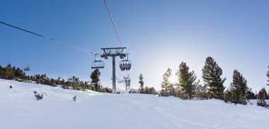 Bulgaristan. Bansko. 10 Şubat 2020 'de Bansko' da bir tatil köyünde. Karlı kayak pistleri ve sandalye kaldırma istasyonları. Güneşli bir günde mavi gökyüzünün altında