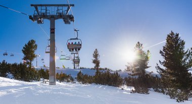 Bulgaristan. Bansko. 10 Şubat 2020 'de Bansko' da bir tatil köyünde. Karlı kayak pistleri ve sandalye kaldırma istasyonları. Güneşli bir günde mavi gökyüzünün altında