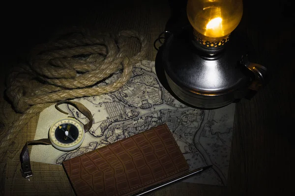 灯油ランプの明かりの下で夜の旅行を計画してた コンパスで古地図を調べノートに書き込む — ストック写真