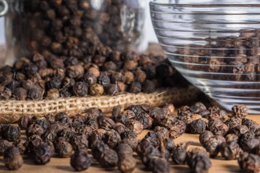 Tahta arka planda ve çuval bezinde kara biber taneleri.