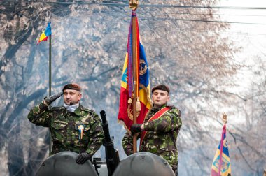 Timisoara, Romanya - 1 Aralık 2017: iki asker Romanya Milli günü geçit töreninde askeri Selam vererek. Askeri zırhlı personel taşıyıcı.