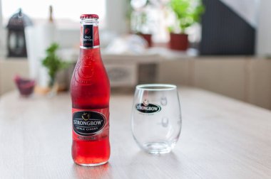 Timisoara, Romanya - 04 Ocak 2018: Strongbow şişe ve cam ahşap bir masa üzerinde. Elma suyu. Kırmızı meyveler.