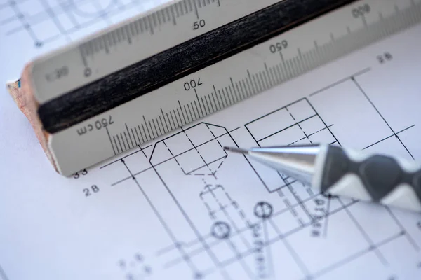 Close-up of a wooden ruler with a blueprint and mechanical pencil in the background. Architect tools. Selective focus.