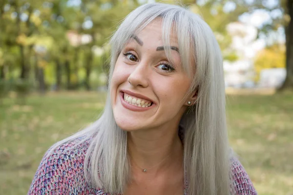 Outdoors portrait of a woman making funny faces. Silver hair.