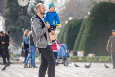 Timisoara, Romanya - 17 Kasım 2019: İnsanlar sokakta yürüyor. Baba ve çocuk. Gerçek insanlar..