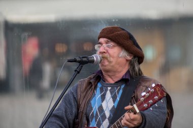 Timisoara, Romanya - 17 Kasım 2019: Adam sokakta şarkı söylüyor ve gitar çalıyor. Gerçek insanlar..