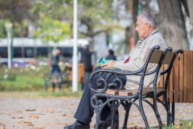 Timisoara, Romanya - 17 Kasım 2019: Parktaki bankta oturan adam. Gerçek insanlar..