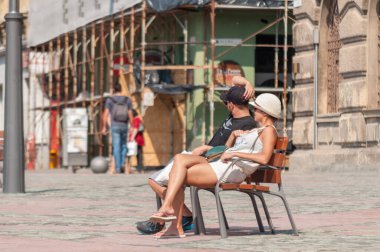 TIMISOARA, ROMANIA - 16 Eylül 2016: İnsanlar sokakta bir bankta oturuyor. Gerçek insanlar..