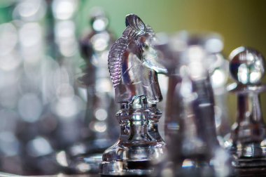 Satranç tahtasının üzerinde duran saydam bir at satranç taşının yakın çekimi. Sığ alan derinliği.